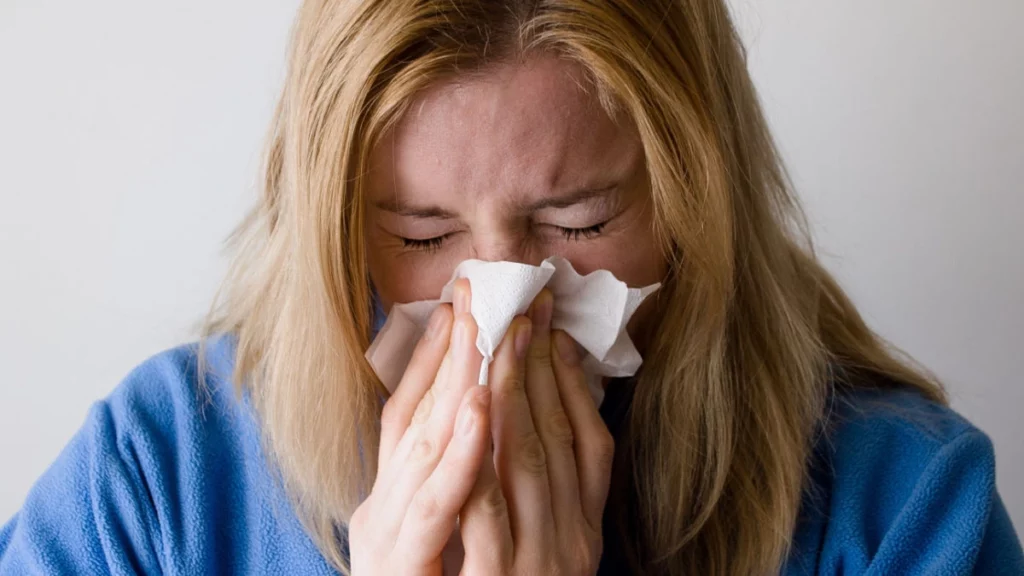 Woman blowing her nose because of seasonal allergies