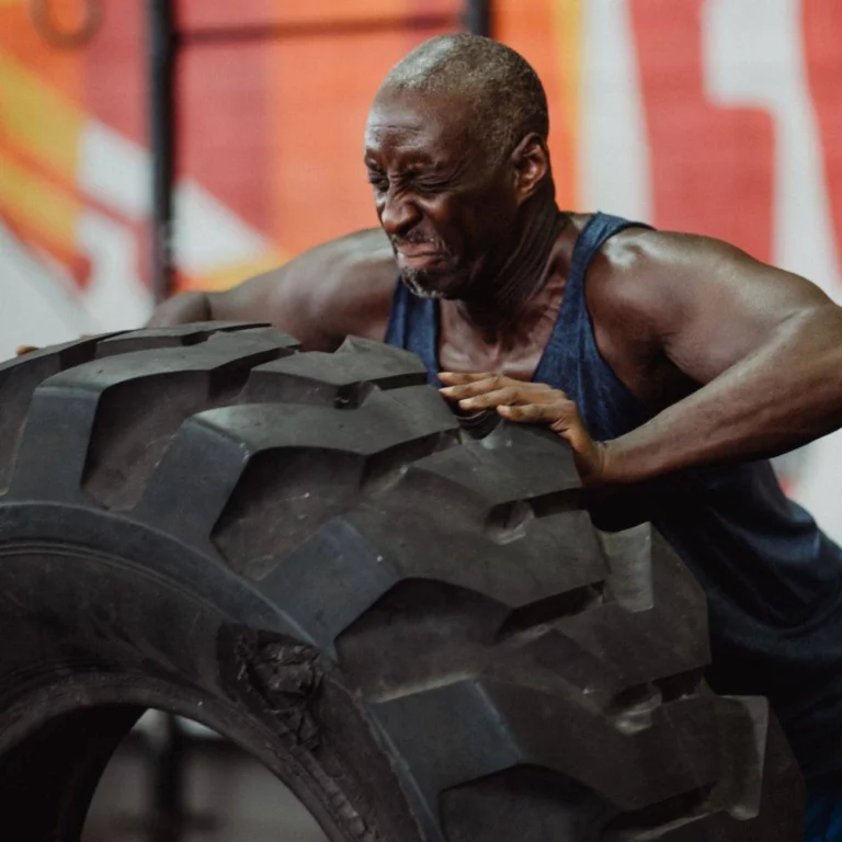 Man straining to push big tire in the gym