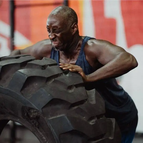 Man straining to push over a giant tire